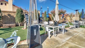 Ein Patio mit Gartenmöbeln, einer hohen Metallkonstruktion und einer Steinmauer.