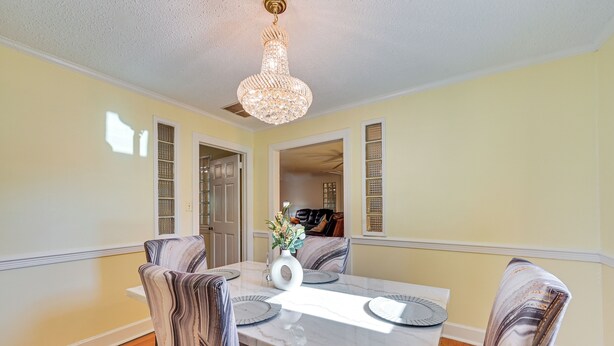 A dining room with a marble table, striped chairs, a chandelier, and a vase with flowers. - Greenville Home: 2 Mi to Downtown! 1 Mi to Ecu! (Greenville)