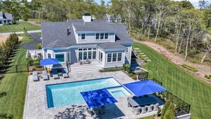 Une grande maison avec une piscine, un espace extérieur aménagé et une pelouse bien entretenue.