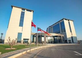 A modern building with a large glass entrance and multiple flags.