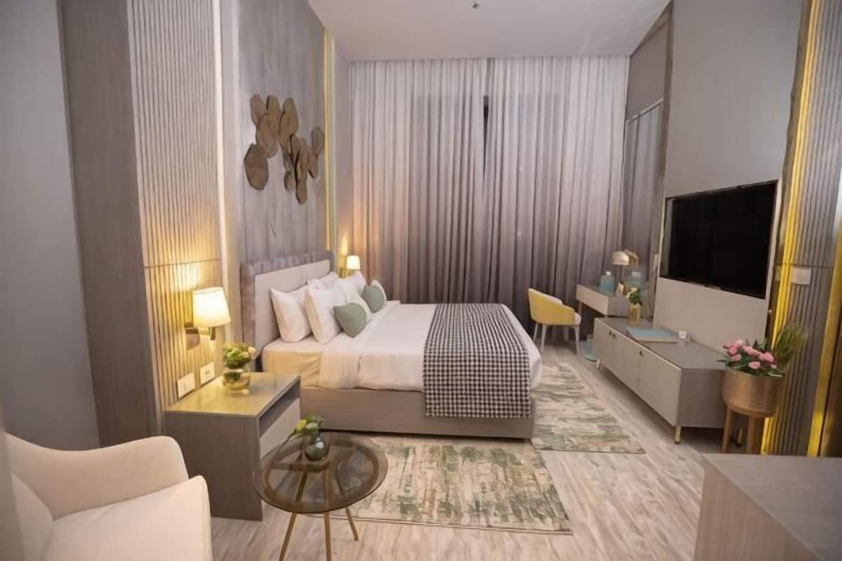 Une chambre d’hôtel moderne équipée d’un lit, de tables de chevet, d’un bureau, d’une télévision et d’un coin salon.