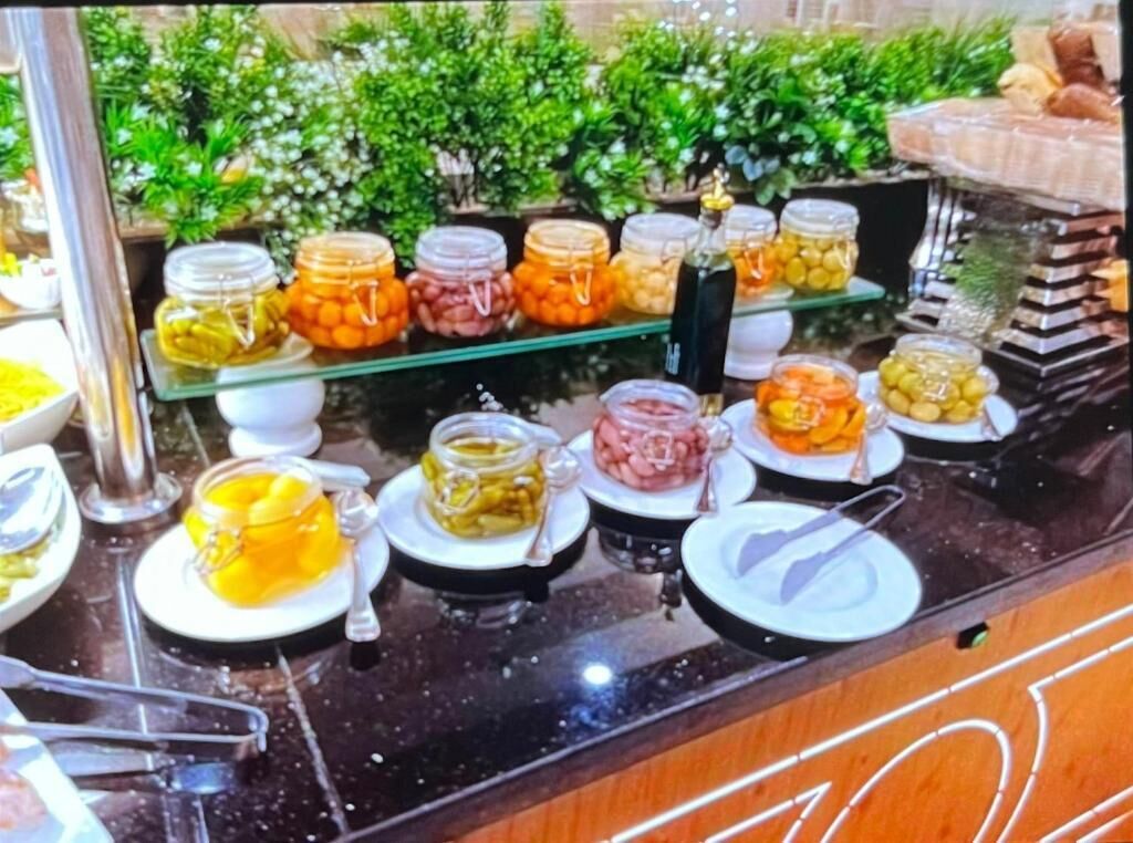 A buffet with various food items including pickles, meats, and fruits.