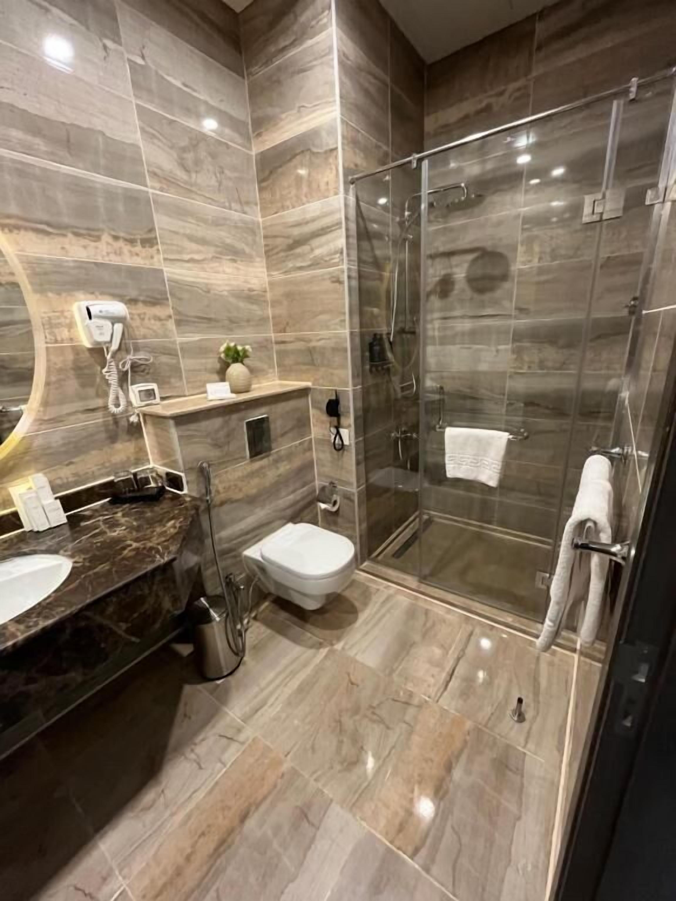 Ein modernes Badezimmer mit Marmorwaschtisch, Duschkabine aus Glas und Toilette.