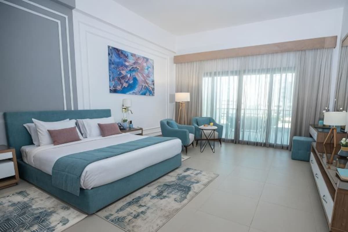 Habitación de hotel con una cama grande, un escritorio, una silla y vistas al exterior.