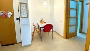 A dining area with a table, chairs, and a hanging light fixture.