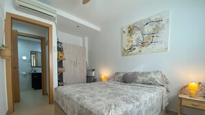 A bedroom with a bed, bedside lamps, a wall-mounted artwork, and a wardrobe.