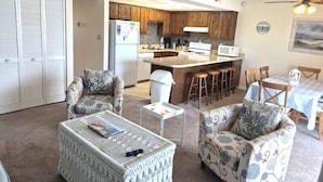 A living room with a sofa, a coffee table, and a dining area with a table and chairs.