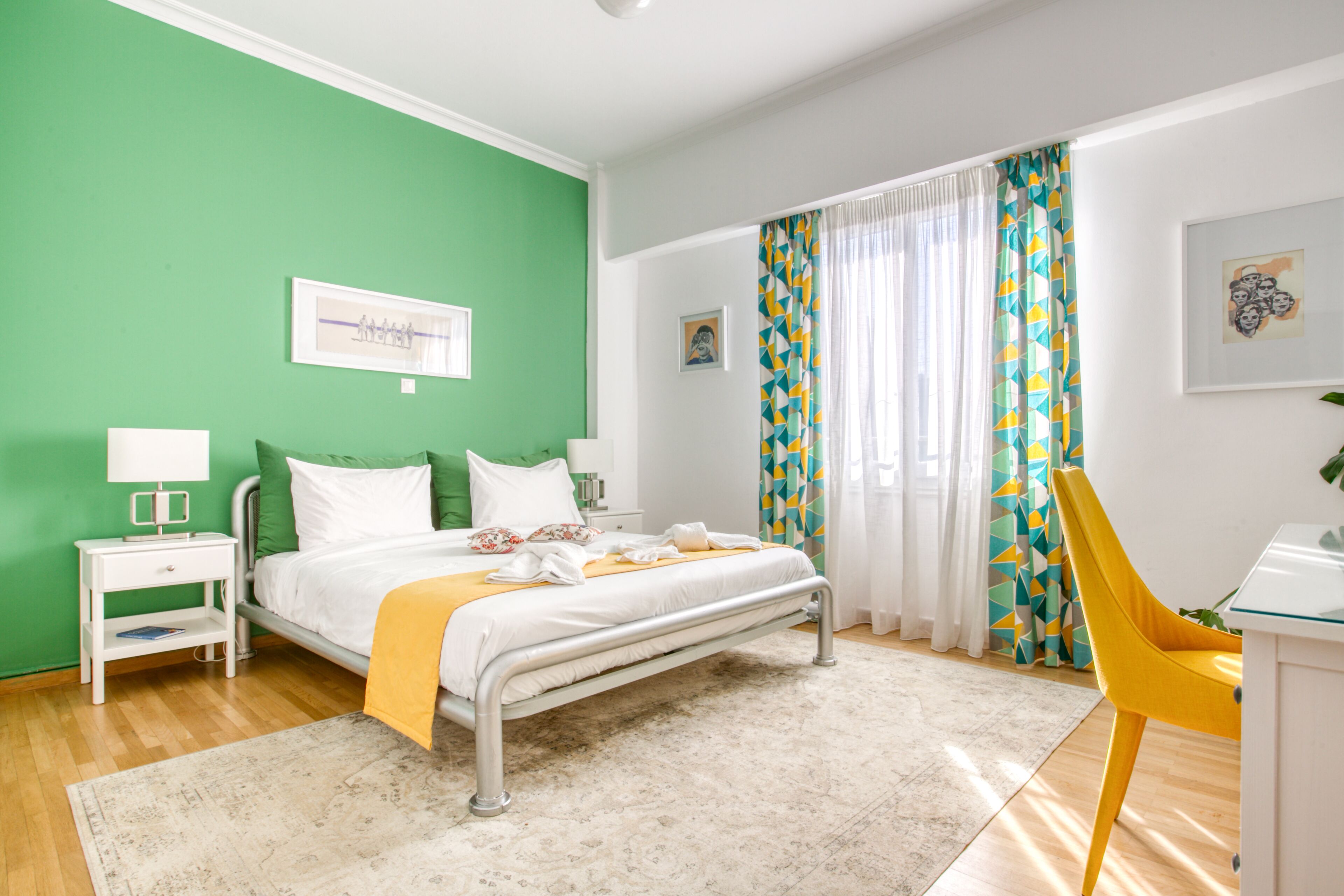 Quarto de hotel com cama, mesa de cabeceira, cadeira e janela com cortinas.