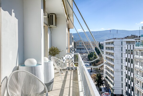 A balcony with a white chair, a small table, and a Dalmatian statue.