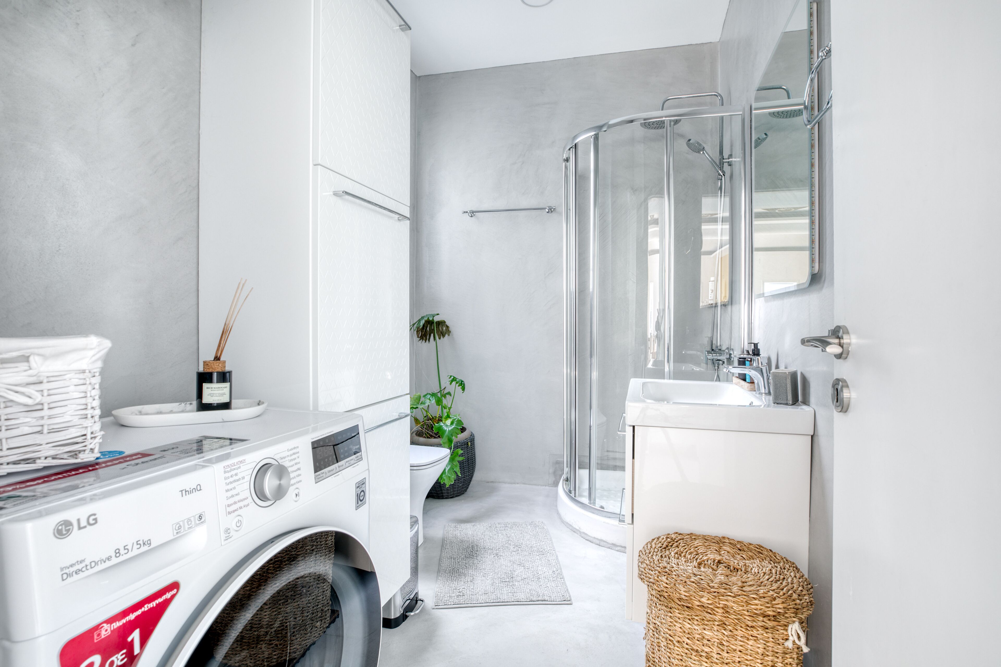 Ein modernes Badezimmer mit Waschmaschine, Duschkabine aus Glas und Waschbecken.