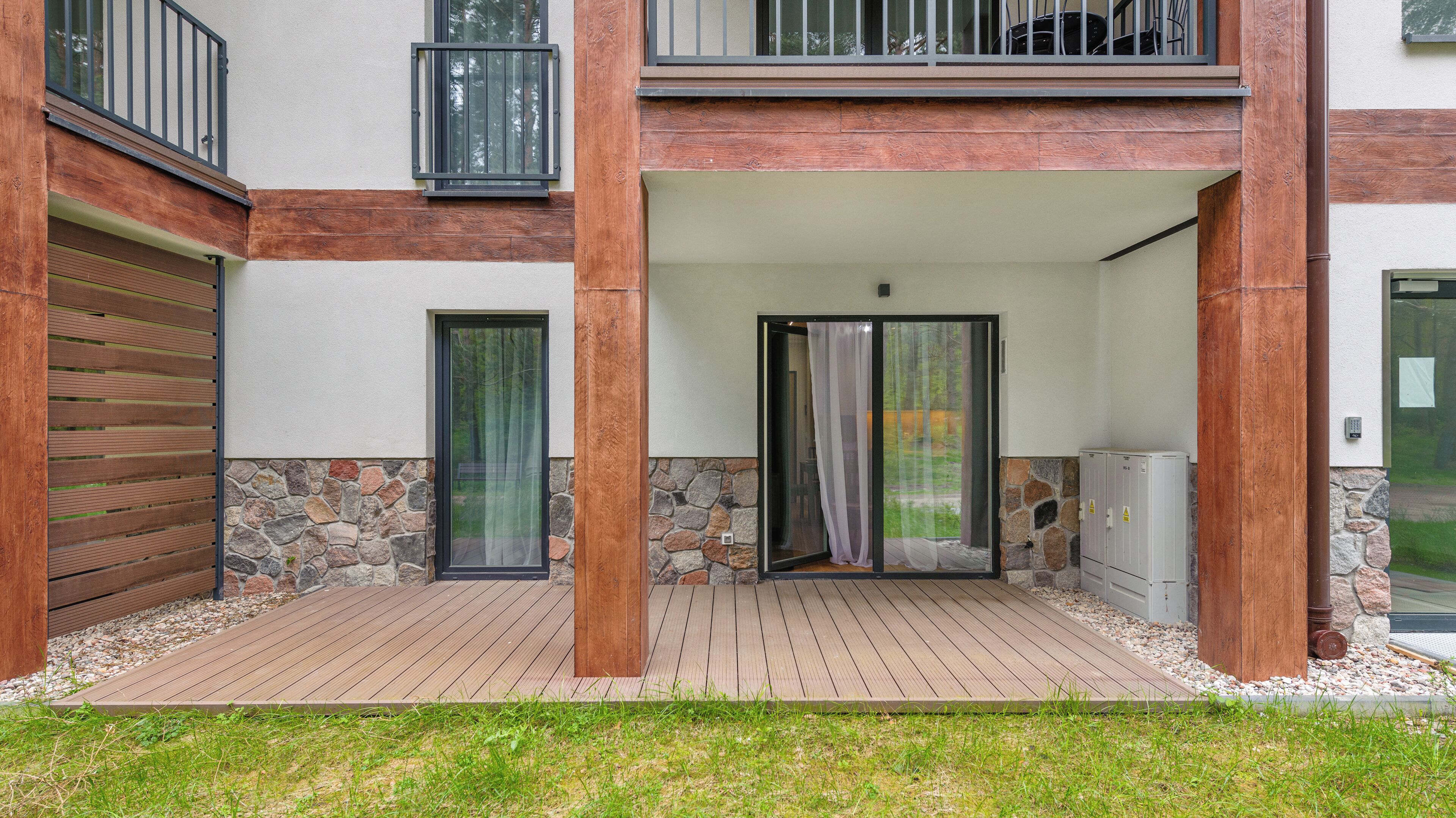 A modern building with a covered outdoor area, stone walls, and wooden flooring.