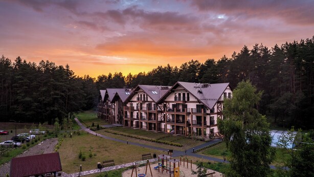 Eine Lodge mit mehreren Gebäuden, einem Spielplatz und einem See.