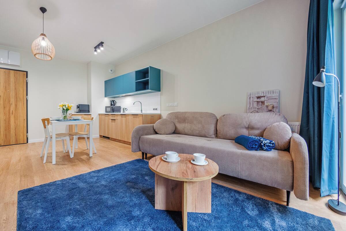 Un apartamento moderno con zona de comedor, kitchenette, sofá y alfombra azul.