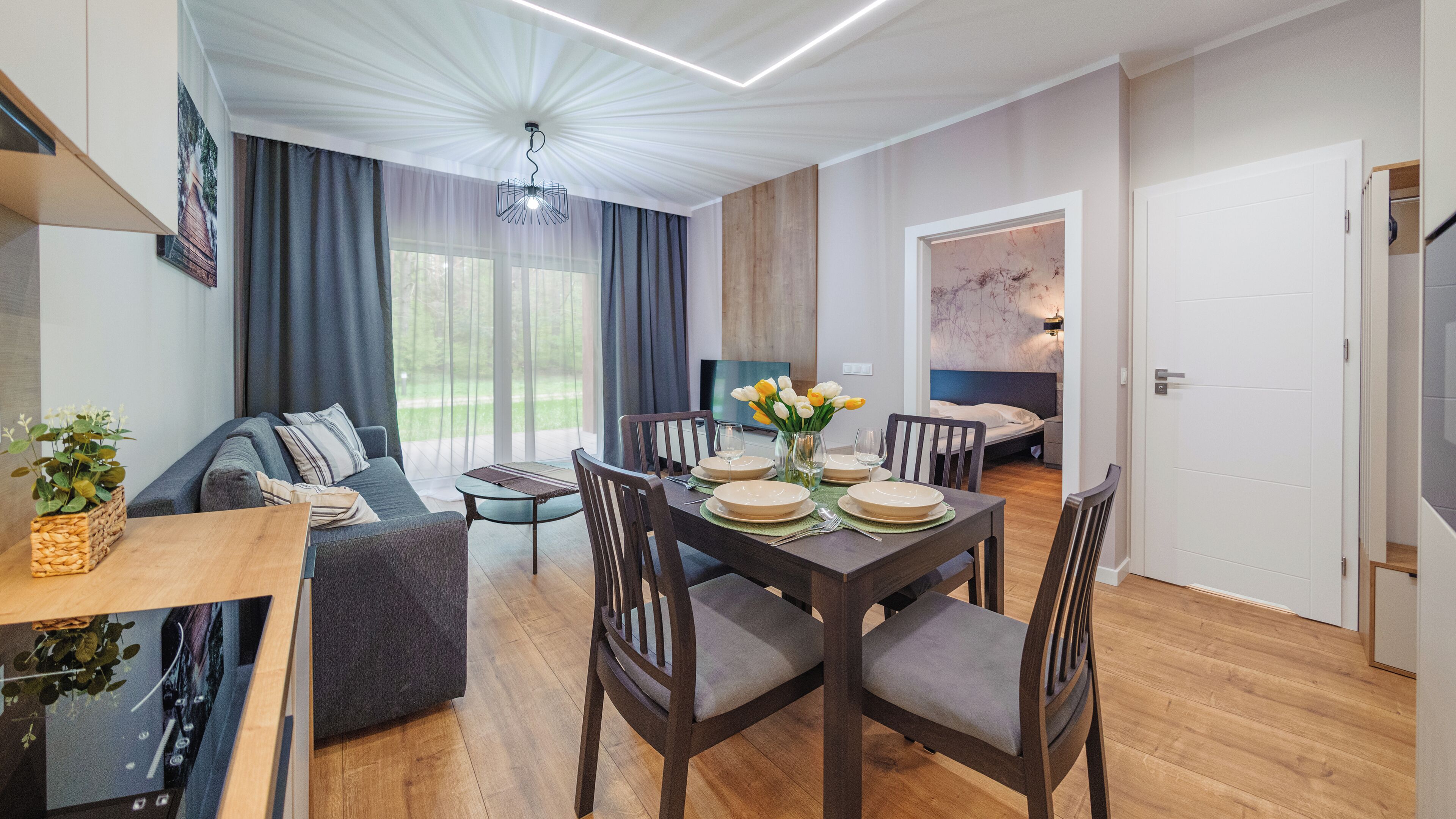 Un salon moderne comprenant un coin repas, un plancher en bois et une grande fenêtre avec des rideaux.