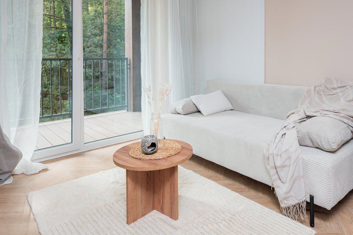 Una sala moderna con un sofá, una mesita de madera y vistas a un balcón.