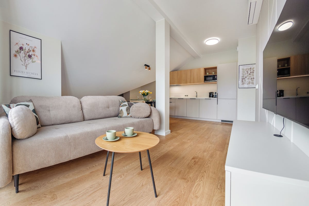 Una sala moderna con un sofá, una mesa de centro y una cocina al fondo.