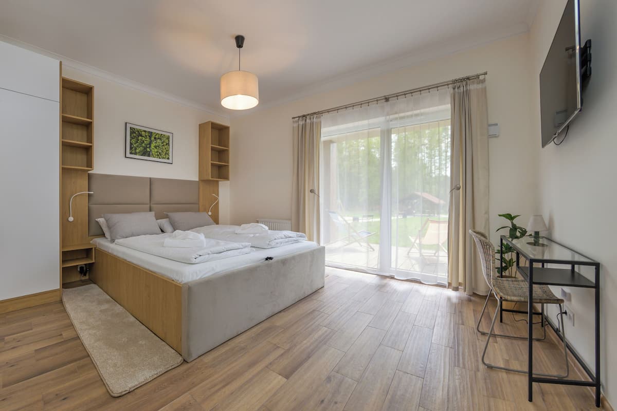 Un dormitorio con cama, estanterías integradas, una mesita de noche, televisor y vistas al exterior.