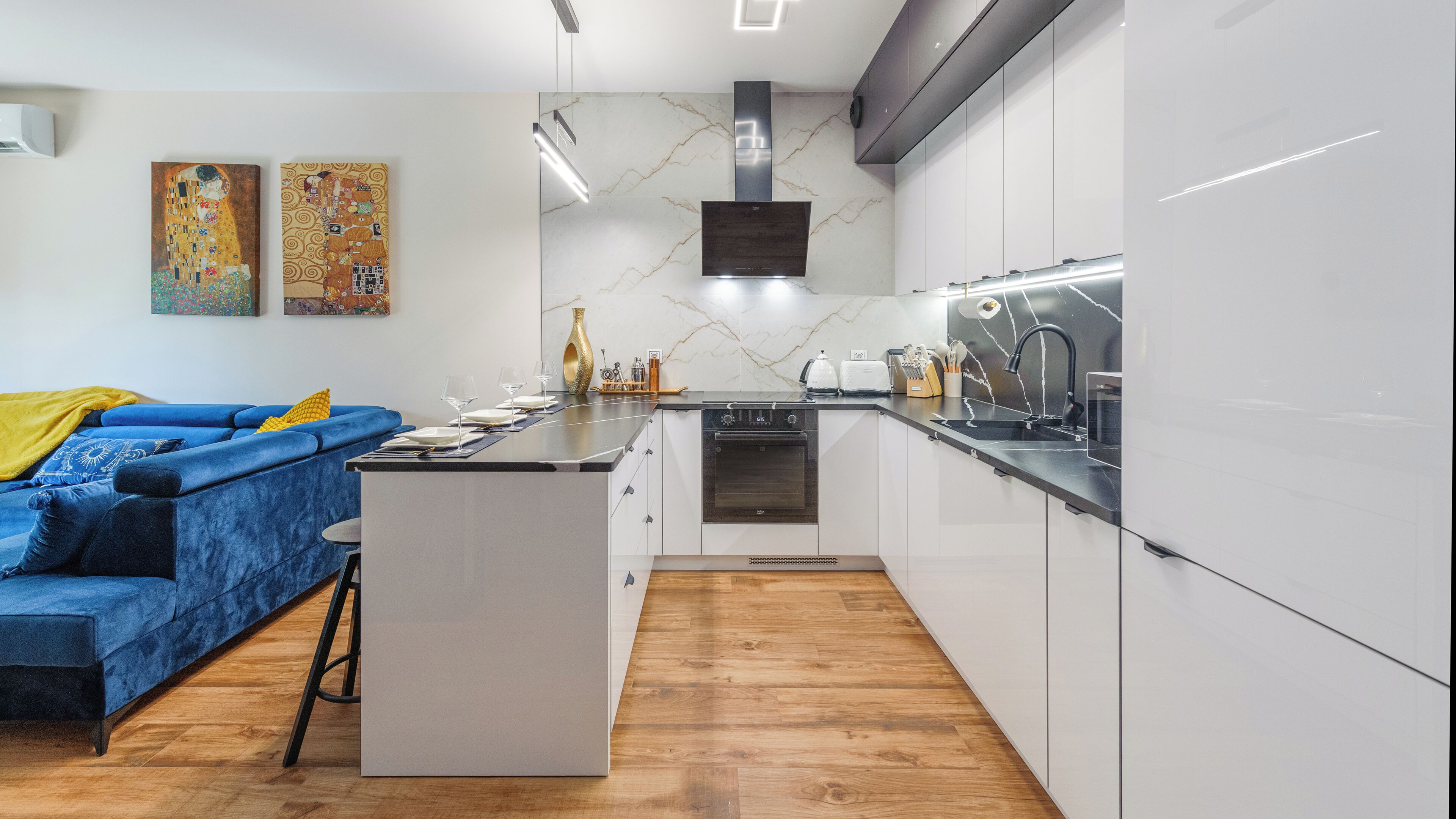 A modern kitchen with white cabinets, a black stove, and a marble backsplash.