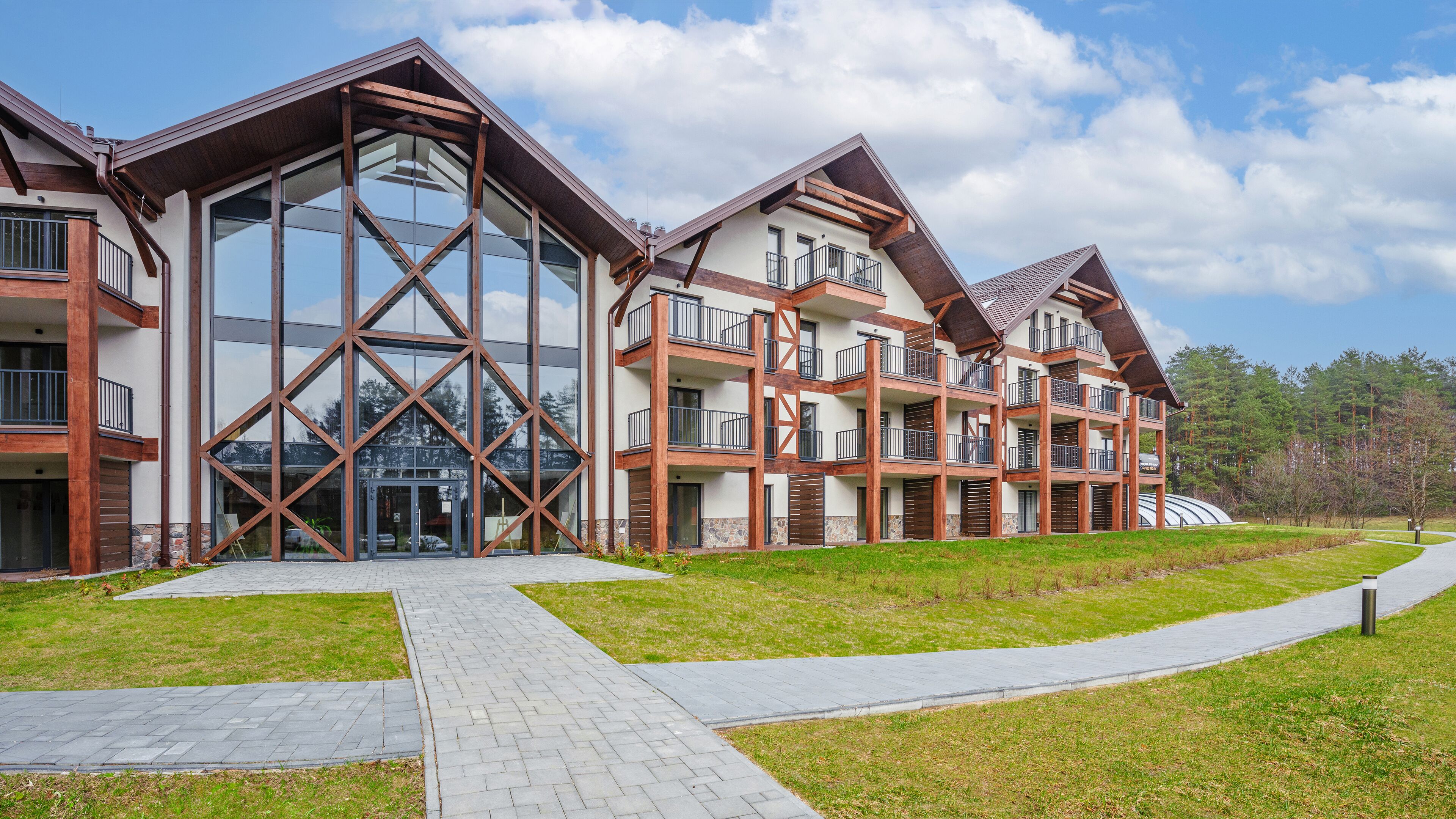 Un immeuble moderne à plusieurs étages, doté de grandes fenêtres en verre, d’une façade en briques et d’une entrée centrale avec une porte en verre.