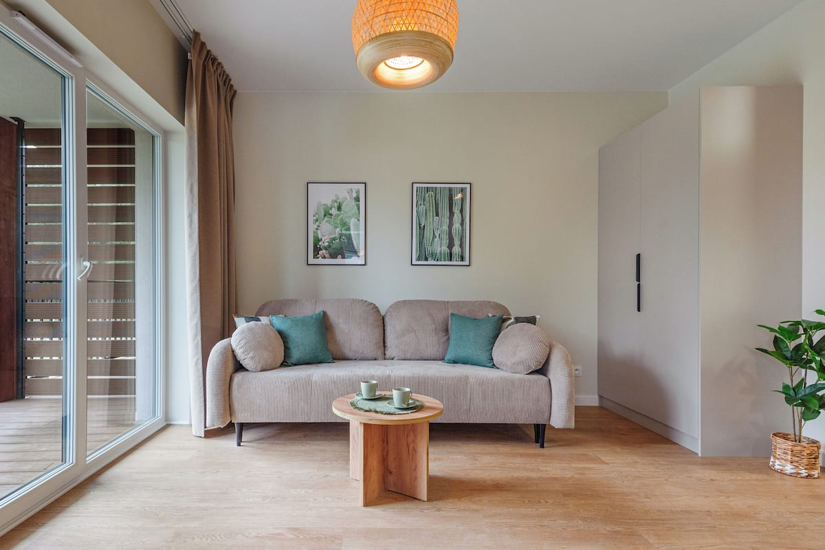 Una sala de estar con un sofá, una mesita de madera y una planta.