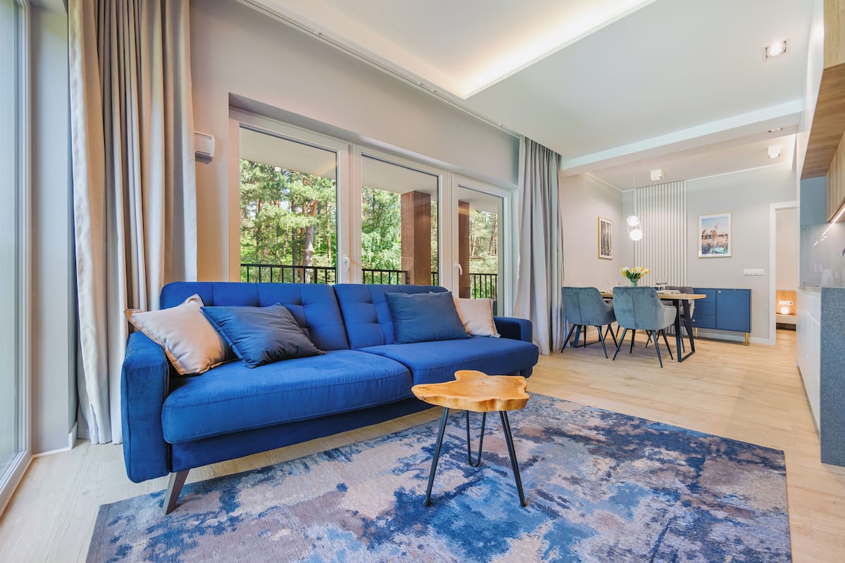 Una sala de estar moderna con un sofá azul, una mesa de centro de madera y un comedor con sillas y una mesa.