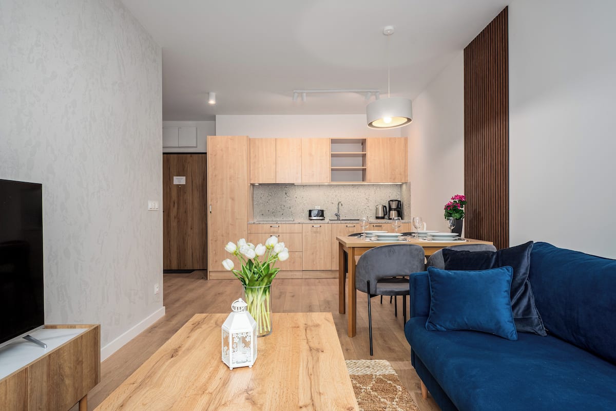 Una sala de estar moderna con televisor, mesa de centro de madera y sofá azul.