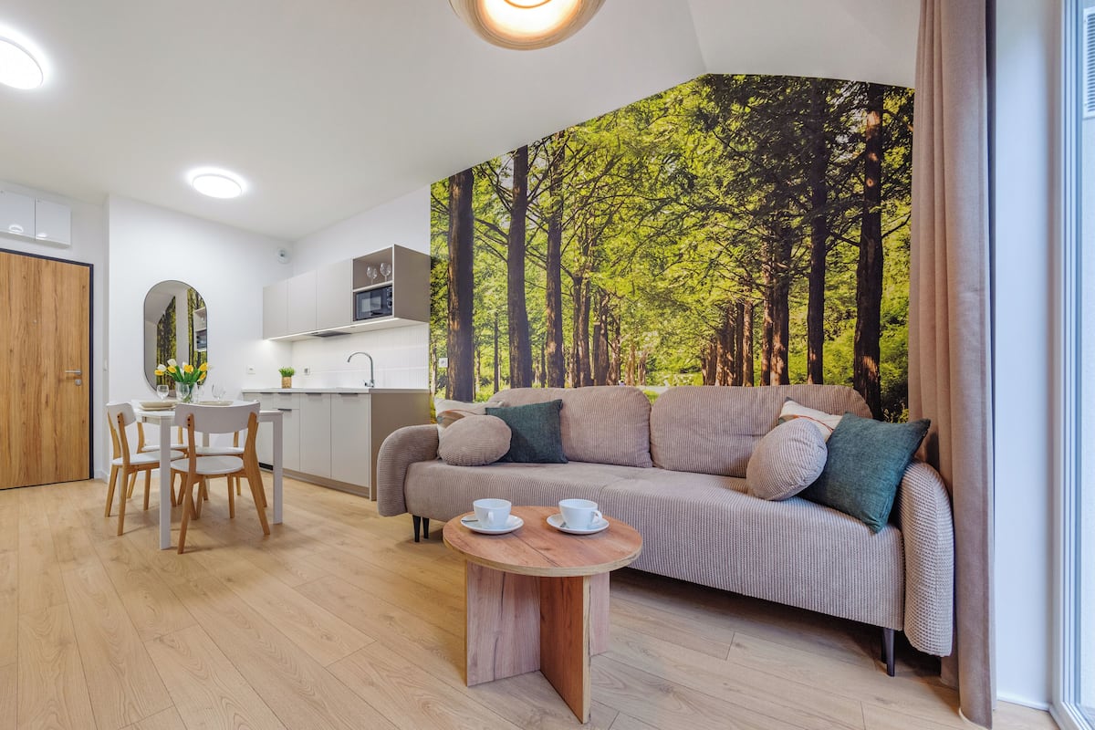 Una habitación moderna con una mesa de comedor, un sofá y un mural de un bosque.