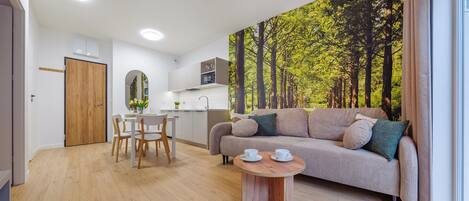 A modern room with a dining table, a sofa, and a mural of a forest.