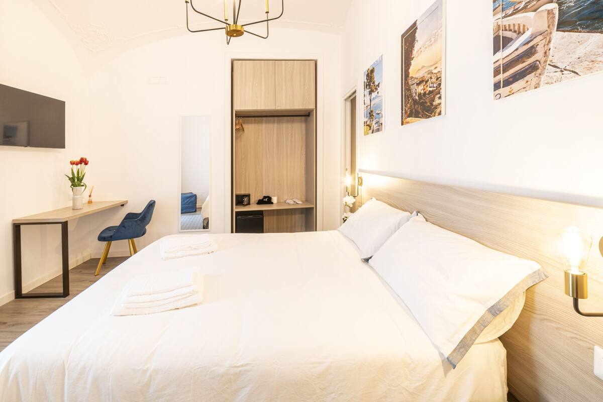Una habitación de hotel moderna con una cama grande, un escritorio y un armario.