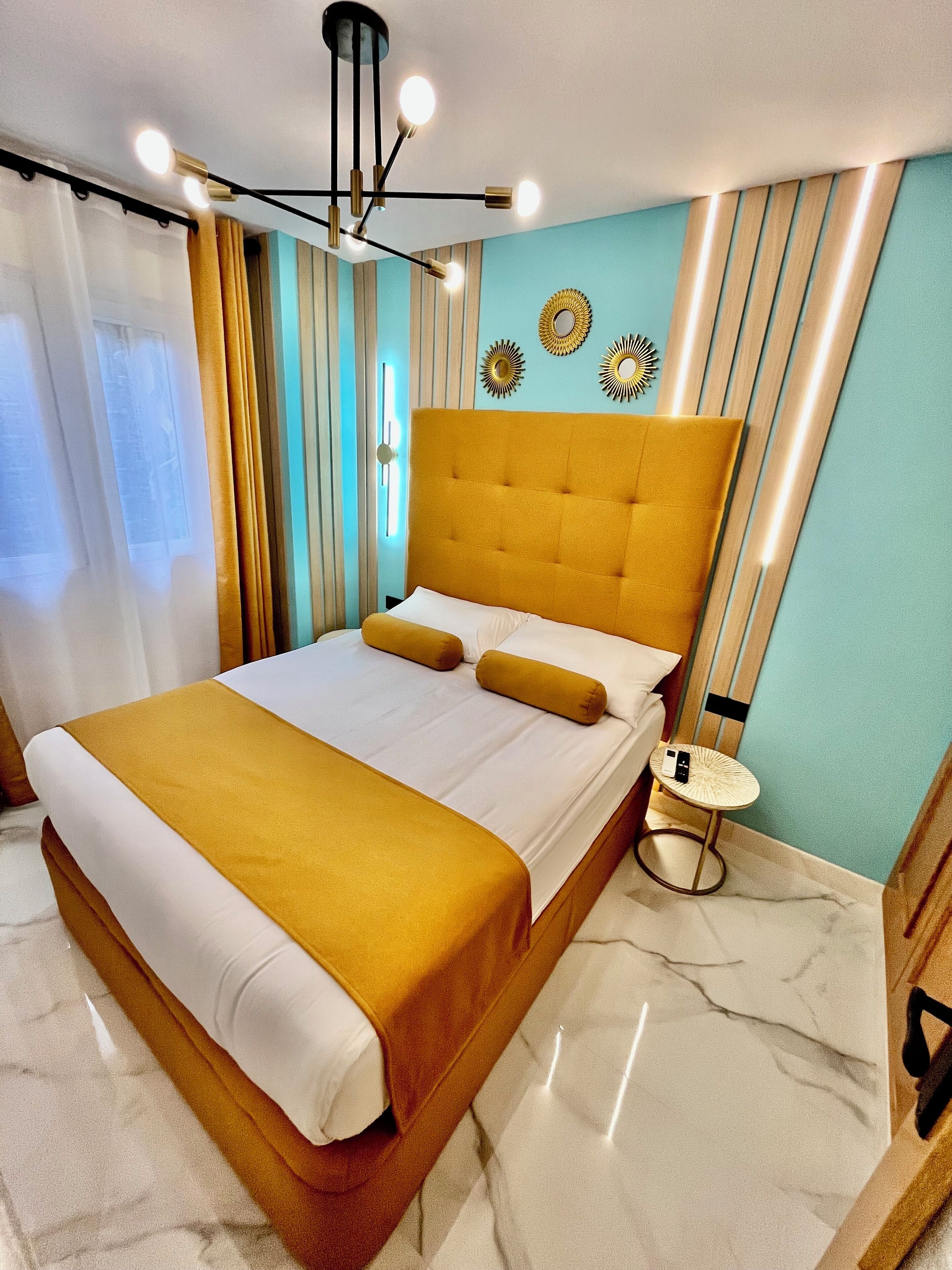 A modern hotel room with a large bed, a bedside table, and decorative wall art.