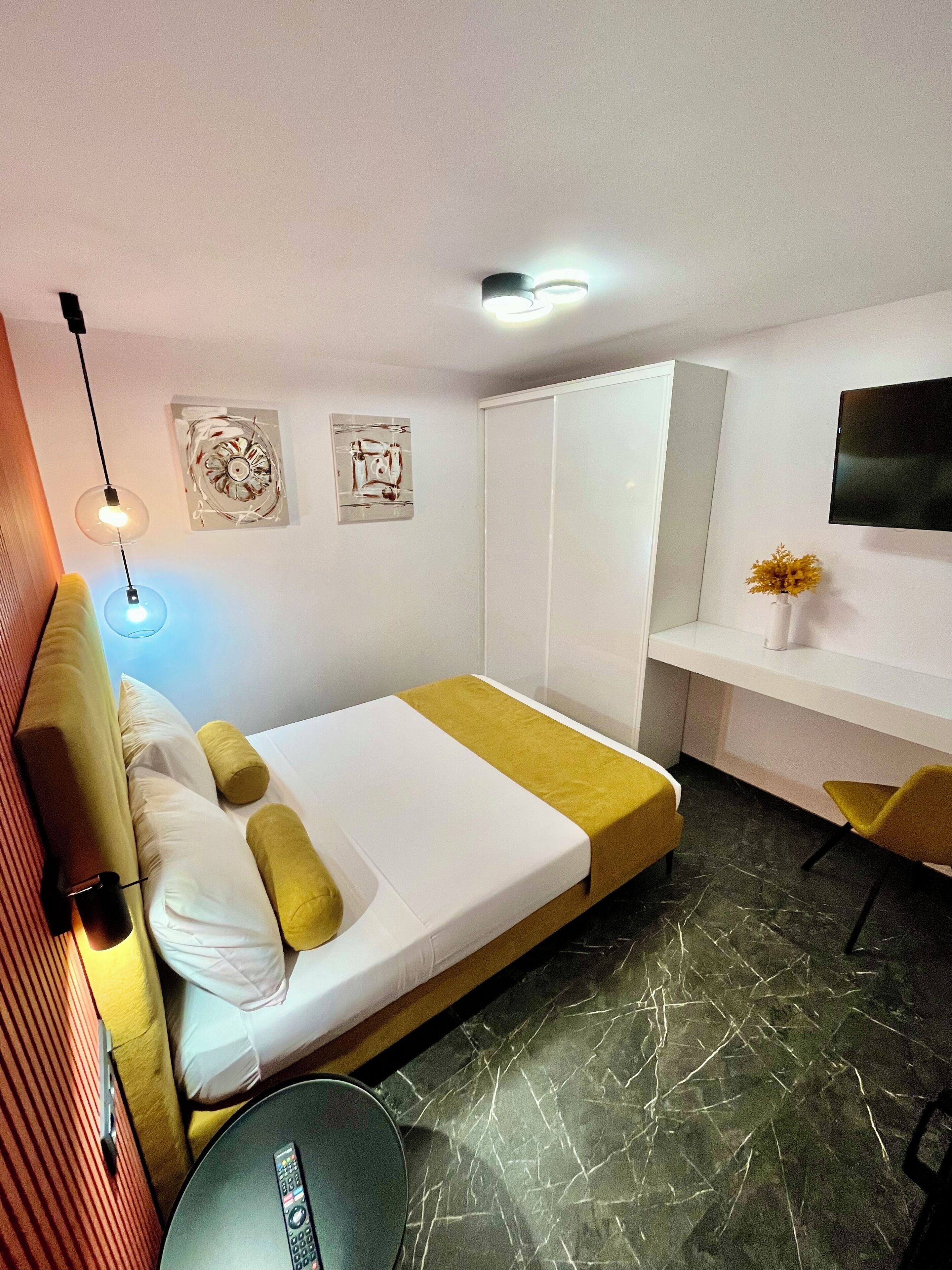 Una habitación de hotel moderna con una cama, mesita de noche y un escritorio con silla.