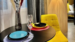 A modern dining area with a black table set for two, a yellow chair, and a vase with decorative feathers. - TresColores  (Alicante)