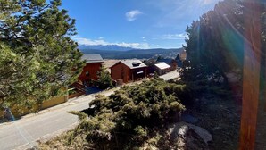 Eine gebirgige Landschaft mit blauem Himmel, einer Straße und mehreren Holzhütten.