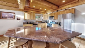 A spacious kitchen with granite countertops, wooden cabinets, and stainless steel appliances.
