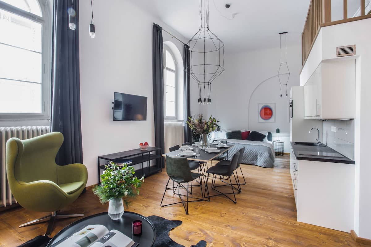A modern living space with a dining area, kitchen, and a cozy seating area.