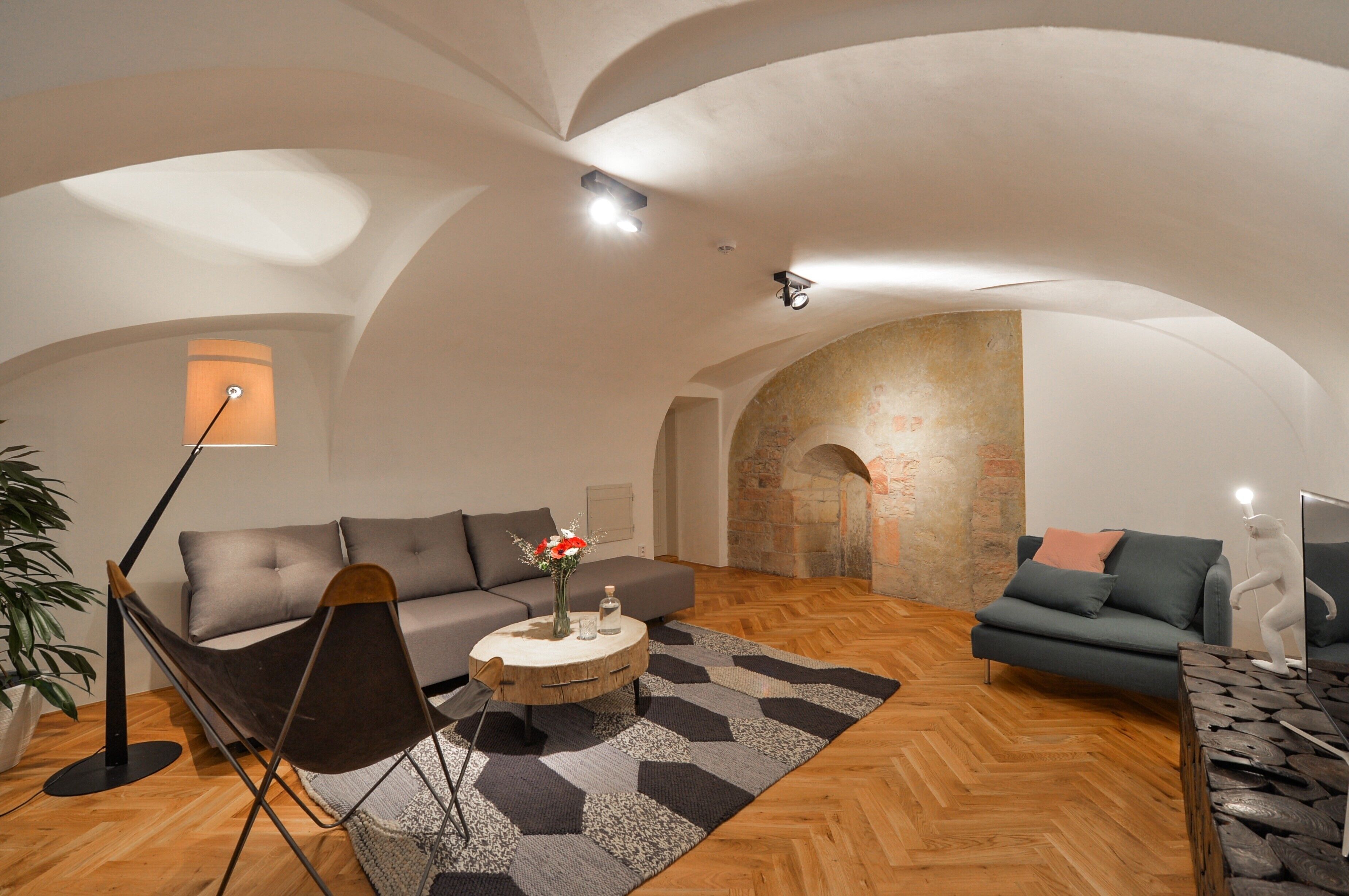 A spacious living room with a high arched ceiling, a fireplace, and a modern sofa set.