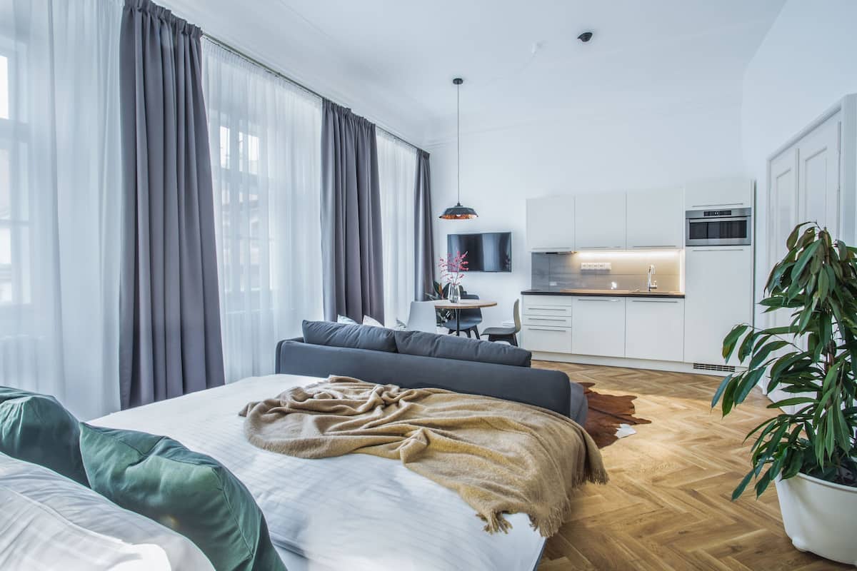 A modern bedroom with a large bed, a sofa, and a dining area.