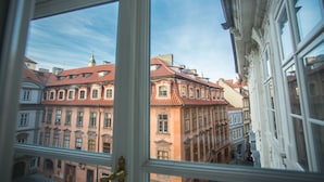 A view through a window of a building with red-tiled roofs and ornate architecture. - Lazenska N4 (Prague)
