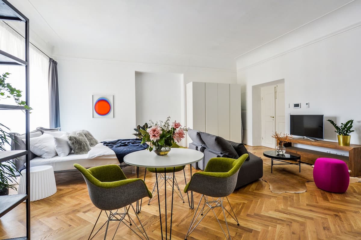 A modern living room with a sofa, green and gray chairs, a round table, and a TV.