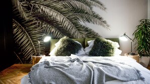 A bed with a white comforter, two green pillows, and a large palm tree in the background. - Lazenska N4 (Prague)