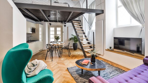 A spacious loft apartment with a high ceiling, a staircase, a dining area, and a living room with a large TV. - Lazenska N4 (Prague)