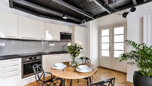 A modern kitchen with white cabinets, a wooden dining table, and black chairs. - Lazenska N4 (Prague)