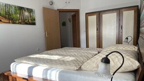 A bedroom with a bed, a bedside table, a lamp, a wardrobe, and a painting on the wall.