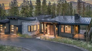Een modern huis met een gevel van natuursteen, grote ramen en een overdekte veranda.