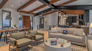 Un salon moderne comprenant un canapé, des fauteuils, une table basse et un coin repas avec une table mise pour le repas.