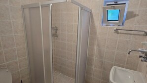 A bathroom with a shower enclosure, toilet, sink, and a small window with a digital display. - Gelincik Apart (Marmaris)