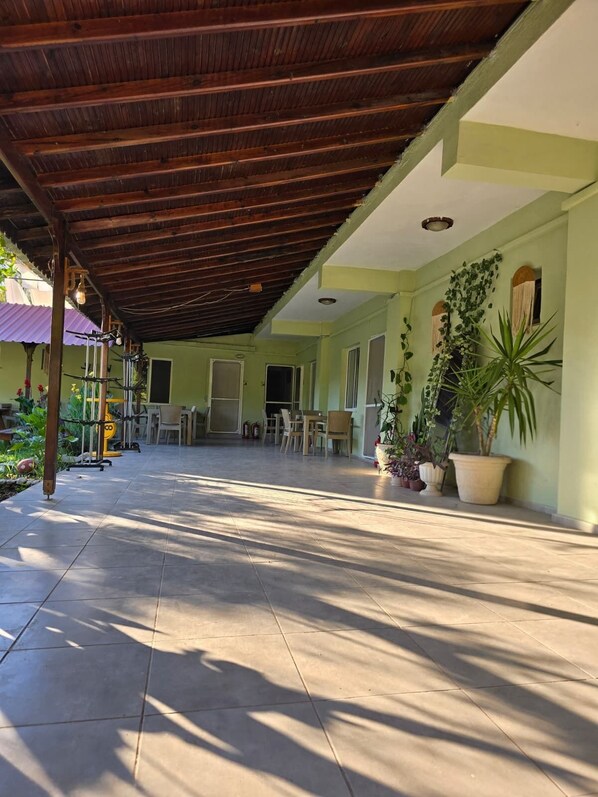 A covered patio area with tiled flooring, a wooden ceiling, and potted plants.