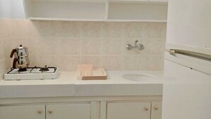 A kitchen with white cabinets, a gas stove, a sink, and a refrigerator. - Gelincik Apart (Marmaris)
