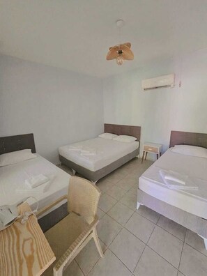 A hotel room with three single beds, a small table, a chair, a ceiling fan, and an air conditioning unit. - Gelincik Apart (Marmaris)