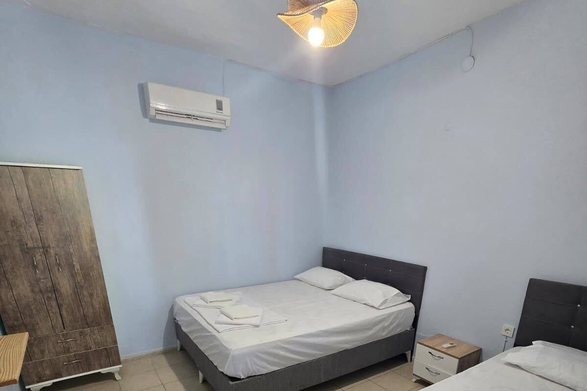 A bedroom with two beds, a wardrobe, a nightstand, and a ceiling fan.